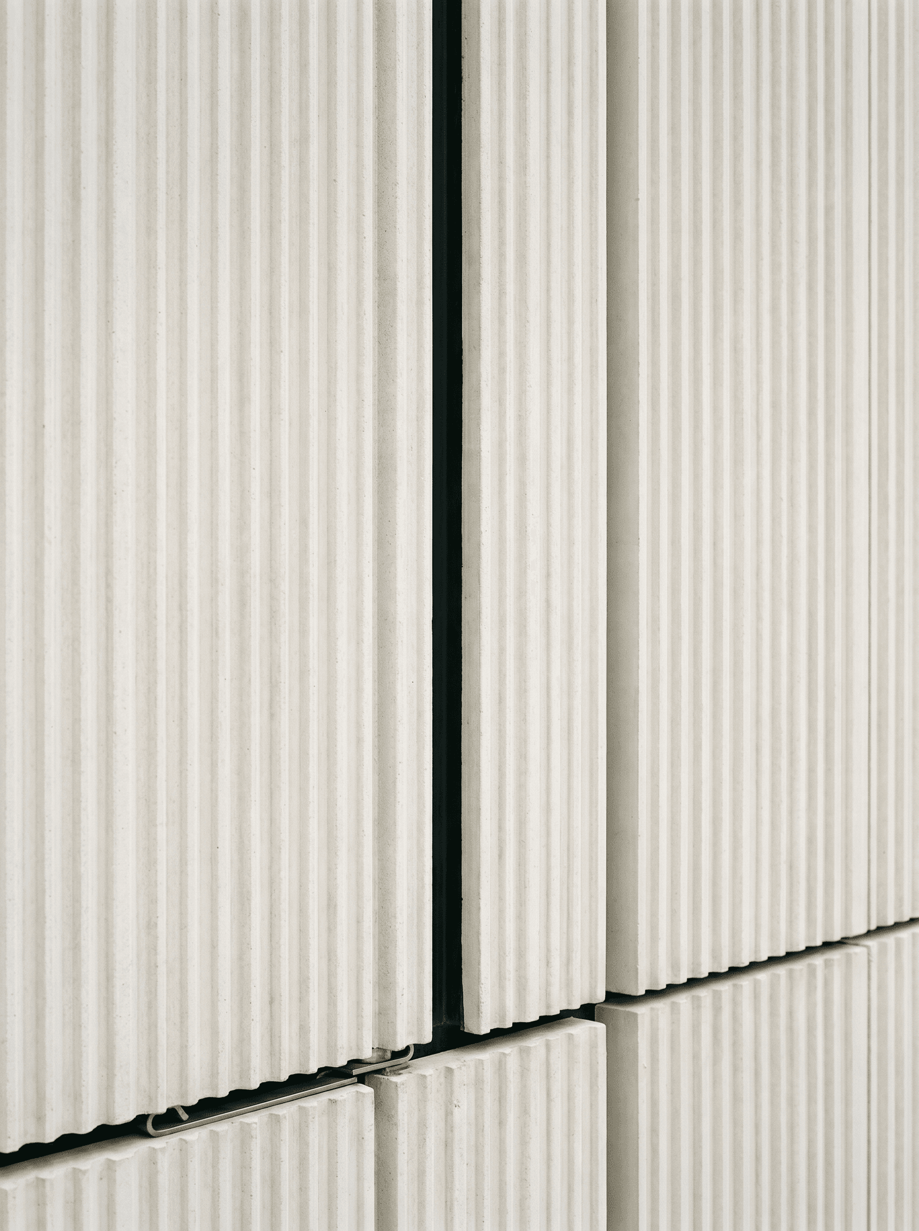 UHPC architectonic panel detail, fine vertical ribbing, recessed joint, hook-and-rail fixing