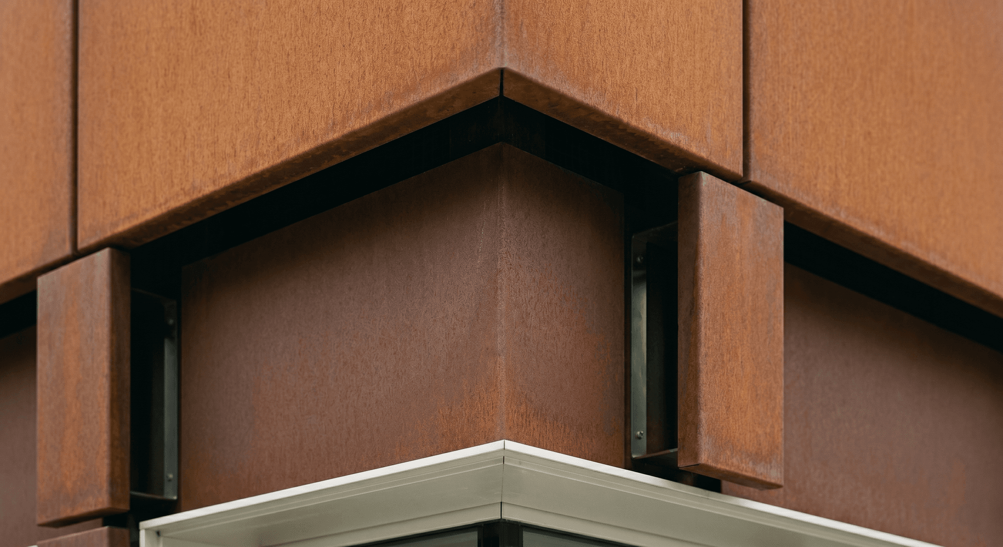 Ventilated corten cladding detail, mitred corner, open shadow gap revealing the ventilated cavity