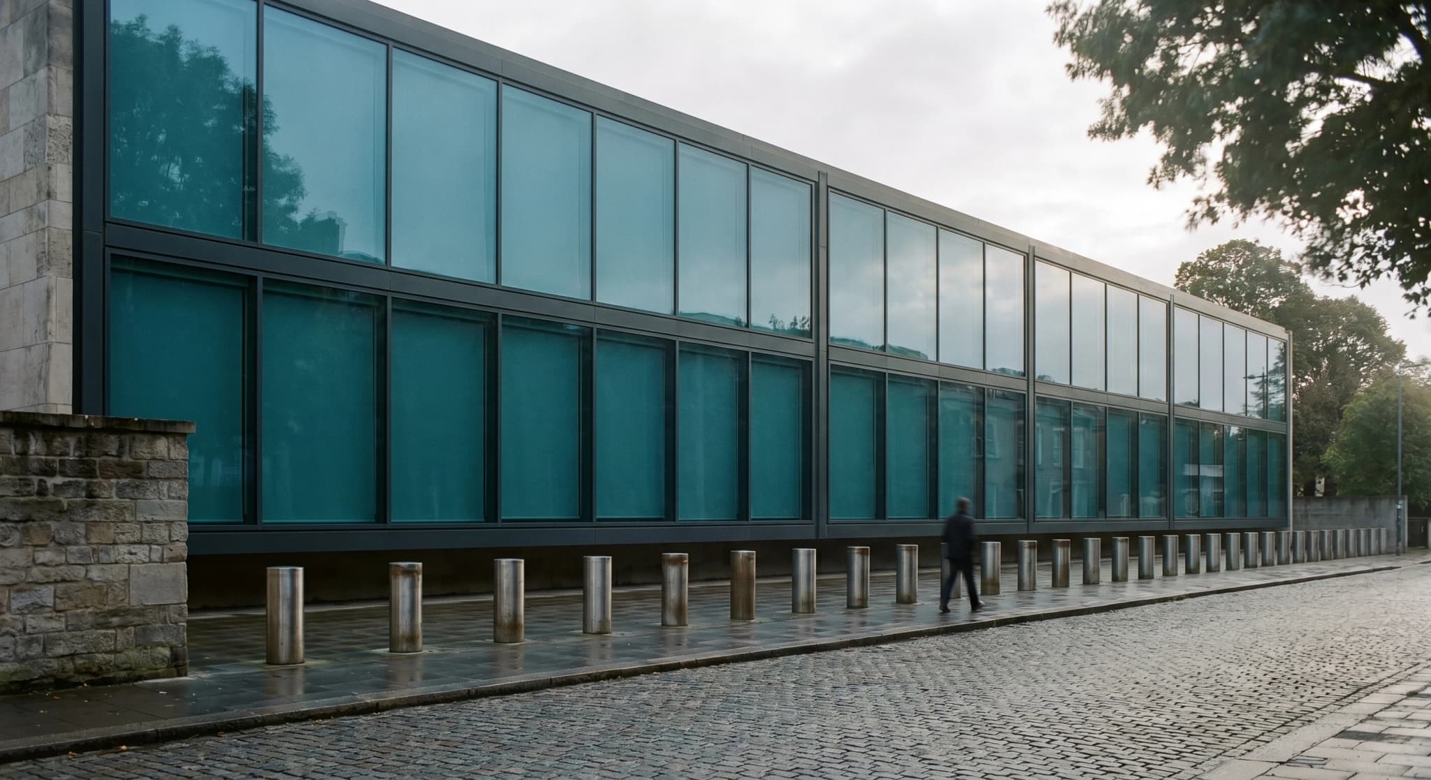 Blast-resilient facade, institutional building with integrated stainless bollards